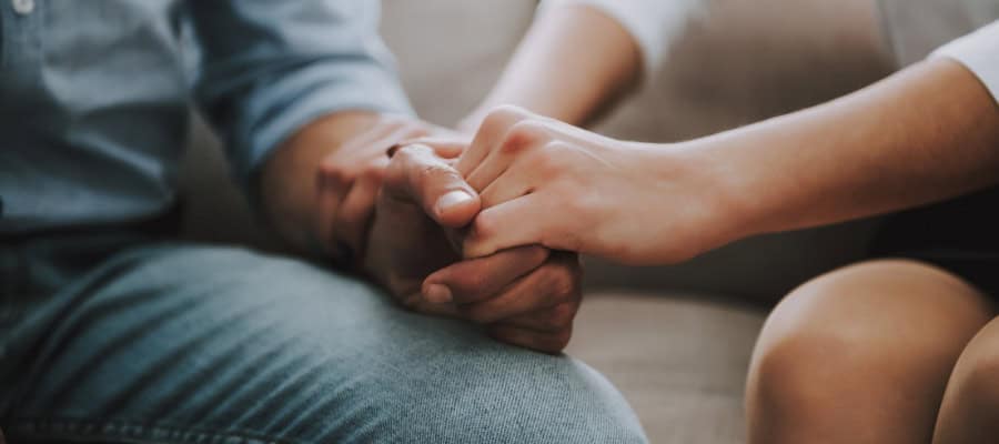 Couple holding hands, showing comfort and forgiveness.