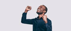 Happy African American man celebrating success with raised fists