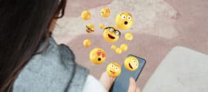 Woman viewing 3D emojis on smartphone; indispensable emotions