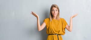 Confused young woman shrugging, demonstrating uncertainty.