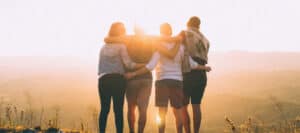 Four friends embrace at sunset, showcasing the strength of their friendship.