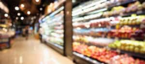 Blurred supermarket aisles with fresh produce and packaged goods. Exploring the morality of food choices.