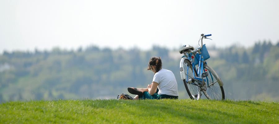 Woman relaxing outdoors with a blue bicycle, enjoying a summer day.