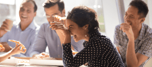 Laughing colleagues enjoy pizza together during a break at work.