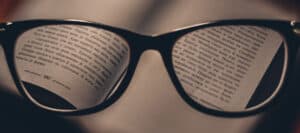 Close-up of eyeglasses on a book, text in a foreign language visible.