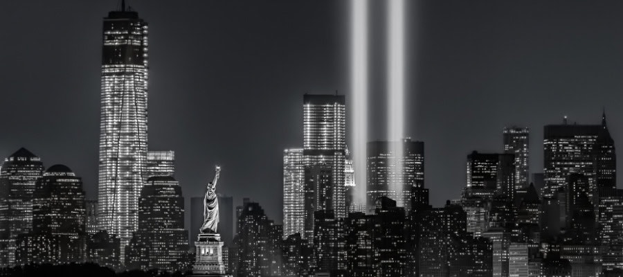 New York City skyline at night, illuminated with Tribute in Light, honoring victims of terrorism.
