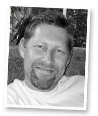 A man with a goatee, smiling gently.