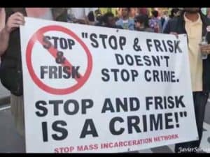 Protest sign: "Stop & Frisk Doesn't Stop Crime. Stop and Frisk is a Crime!" Demonstrates racial profiling concerns.
