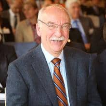 Smiling man in suit, possibly discussing gut feelings and decision-making.