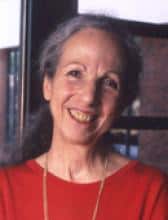 Portrait of a smiling older woman with gray hair, wearing a red shirt.