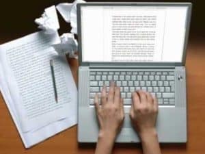 Person typing on laptop, crumpled paper nearby; cooperation and conflict.