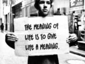 Person holding a sign that reads: "The meaning of life is to give life a meaning.