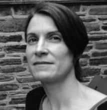 Black and white headshot of a woman against a brick wall