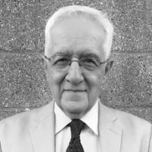 Black and white portrait of an older man wearing glasses and a suit.