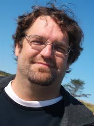 Headshot of a man with glasses and short brown hair
