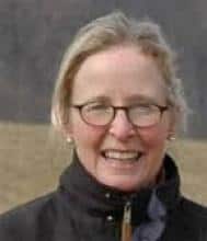 Smiling woman wearing glasses and a dark jacket