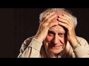 Close-up portrait of philosopher Karl Popper, hands to his face.