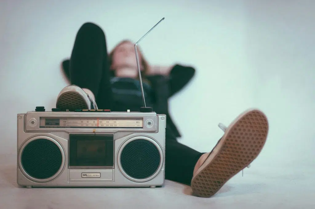 Person relaxing with feet up, listening to a vintage boombox.
