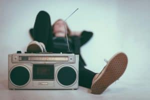 Person relaxing with feet up, listening to a vintage boombox.