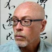 Portrait of a balding man with glasses, thoughtful expression.