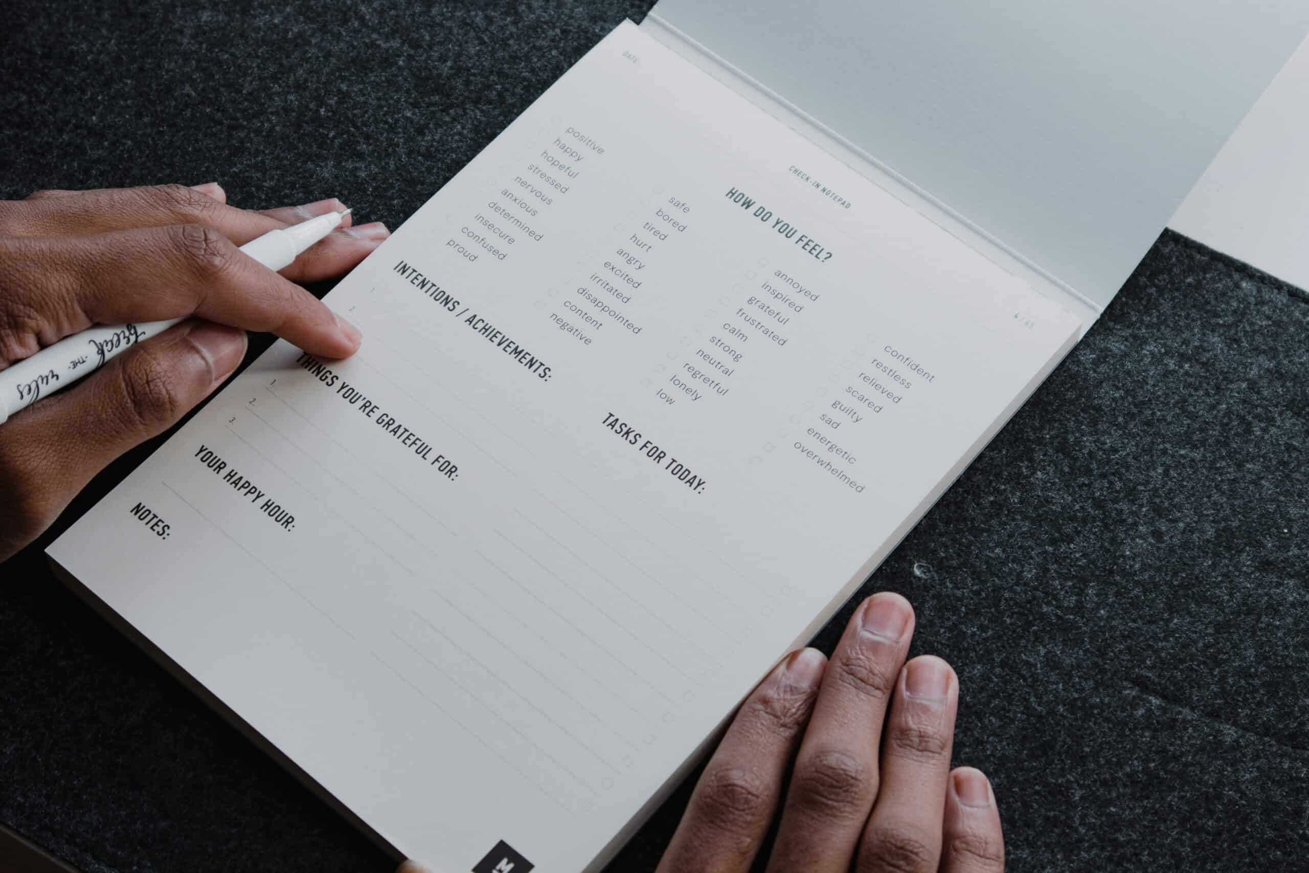 Person filling out a daily habit tracking notepad with "How Do You Feel?" checklist.