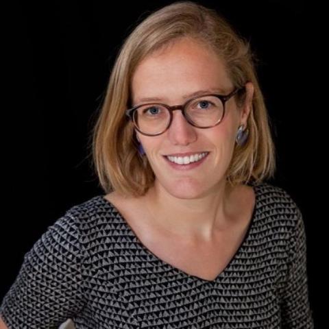Portrait of a smiling woman with short blonde hair and glasses.