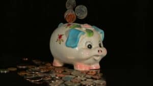 Ceramic piggy bank with coins, symbolizing savings and economics.