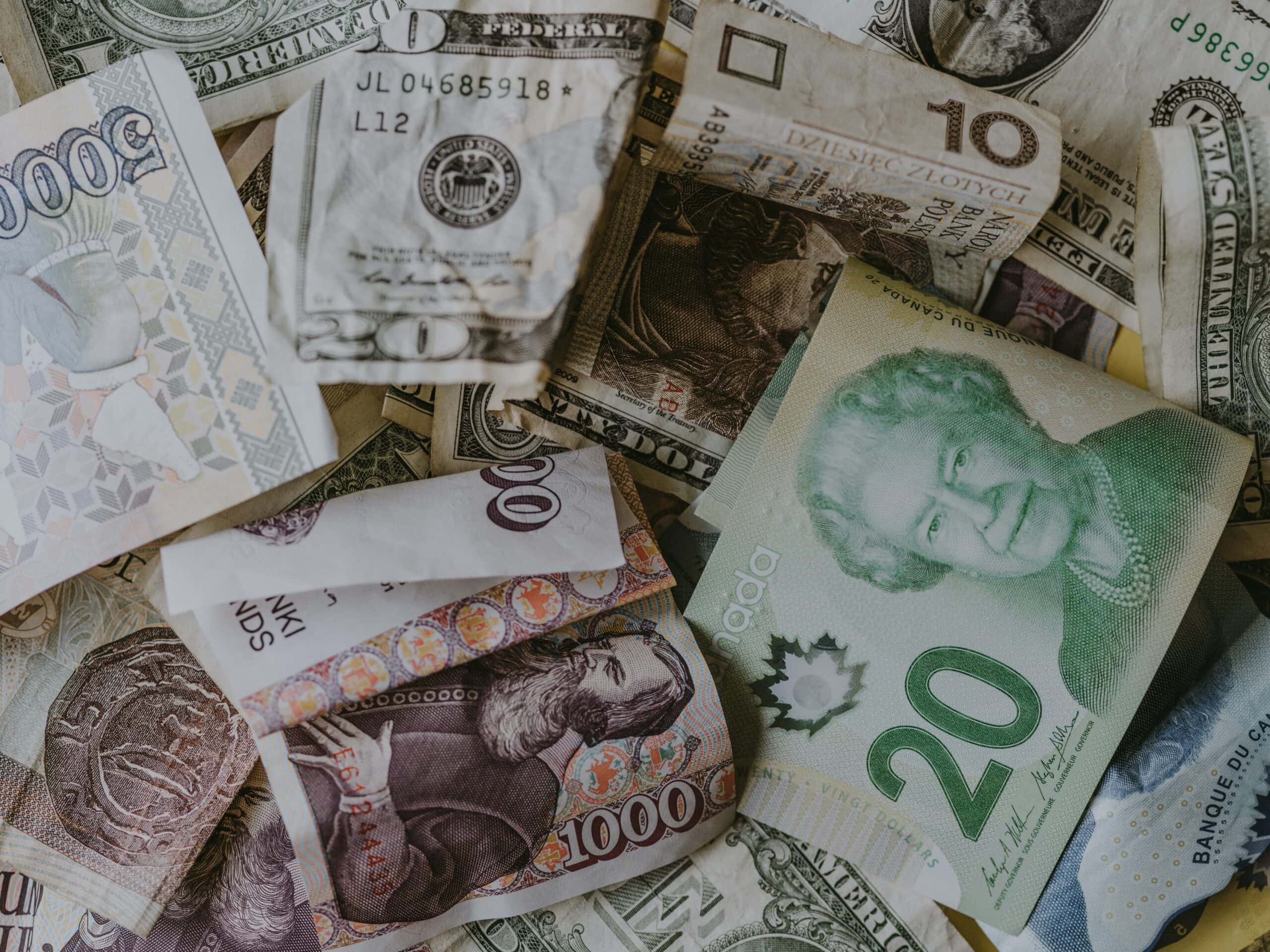 Pile of global currency, including US dollars, Canadian dollars, and Polish zloty. Money from around the world.