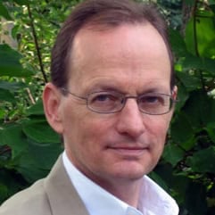 Portrait of a thoughtful man with glasses, possibly discussing Dostoevsky.