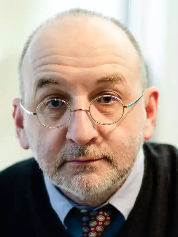 Portrait of a man with glasses and a beard, possibly discussing perception.