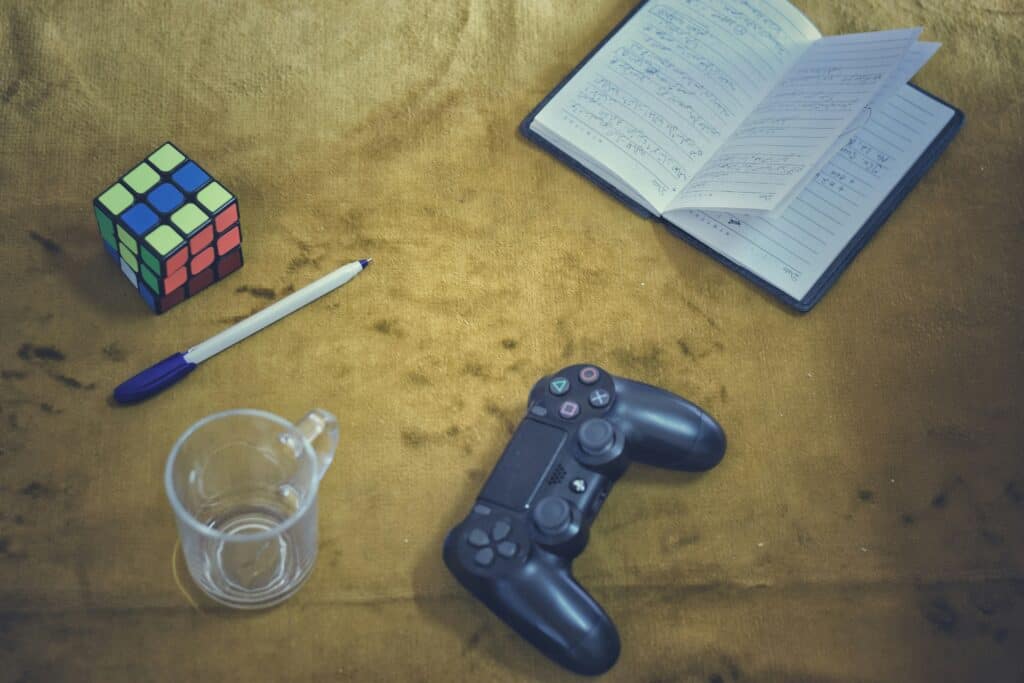 Rubik's cube, notebook, and game controller on a textured surface