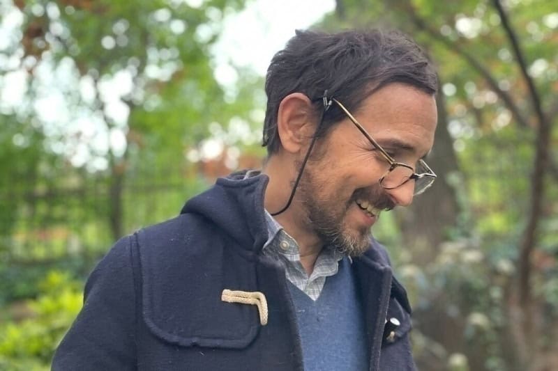 Man with glasses smiling outdoors, inspired by Viktor Frankl and the meaning of life.